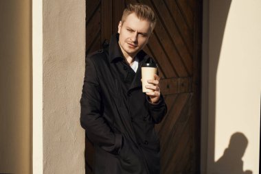 Karanlık montlu genç yakışıklı adam portresi fincan kahve duran eski gate yakınındaki