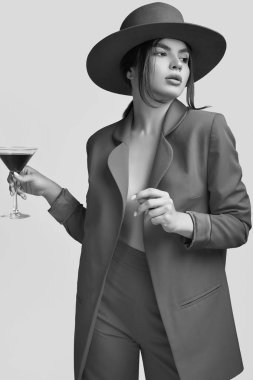 Bir kırmızı moda bir takim elbisesi ve Studio beyaz arka plan üzerinde izole geniş alkolle kokteyl zarif güzel kadın portresi