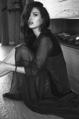 Muhteşem seksi esmer modeli moda kırmızı elbiseli şömine poz portresi. İç ateş.