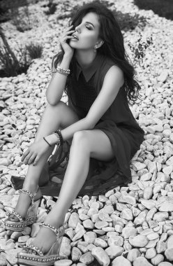 Bahçe beyaz kayaların üzerinde poz moda kırmızı elbiseli güzel şehvetli esmer modeli portresi