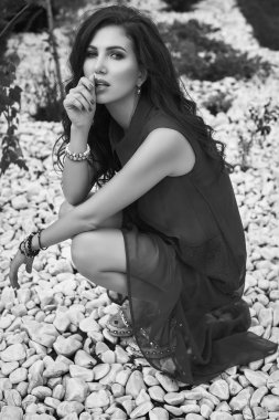 Bahçe beyaz kayaların üzerinde poz moda kırmızı elbiseli güzel şehvetli esmer modeli portresi