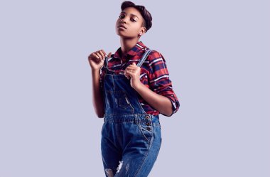Şehvetli bir ekose gömlek ve denim tulum Studio renkli arka plan üzerinde poz kısa saçlı Glamour zarif siyah hippi kız portresi