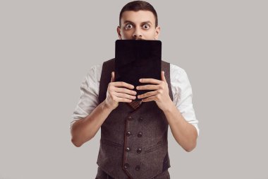 Yakışıklı genç emin Arapça işadamı yün kahverengi takım süslü bıyıklı portresi tablet studio arka plan üzerinde tutar.