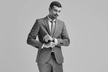 Yakışıklı genç emin Arapça işadamı moda gri tam süslü bıyıklı portresi uygun onun kol studio arka plan üzerinde ayarlama