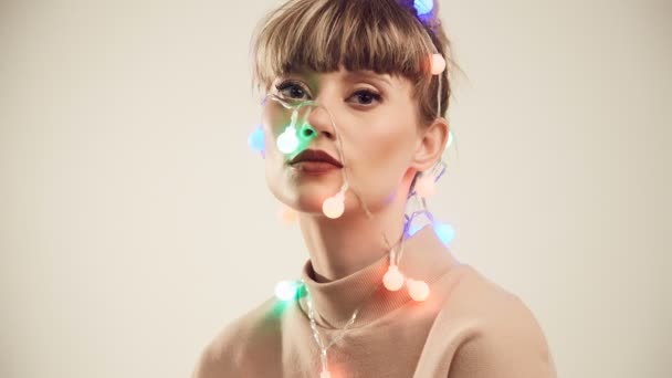 頭の上のクリスマス ライトで美しいブロンド女性のファッション明るい肖像画 スタジオ撮影 — ストック動画
