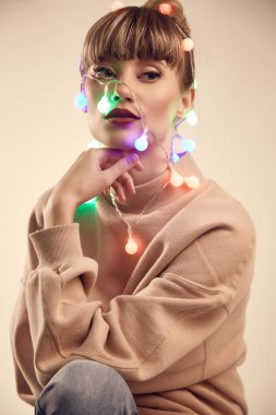 Moda güzel sarışın kadının kafasına Noel ışıkları ile parlak pozitif portre. Stüdyo çekimi.