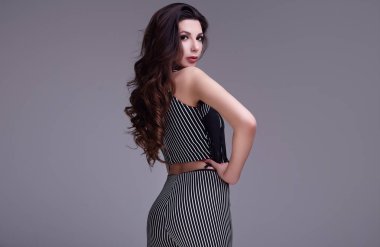 Studio gri arka plan üzerinde poz şık elbiseli uzun saçlı zarif güzel kadın portresi