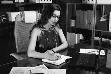 Genç güzel iş kadını moda takım elbise ve şık siyah bilgisayar masa başında çalışma gözlük portresi