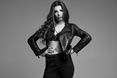 Studio gri arka plan üzerinde deri ceketli uzun saçlı Genç seksi kız portresi