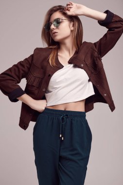 Sevimli Genç kız bardaklarda gri arka plan üzerinde poz moda ceket ve renk portresi. Stüdyo çekimi.