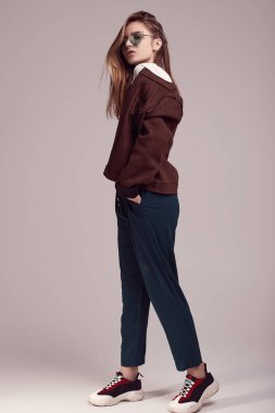 Sevimli Genç kız bardaklarda gri arka plan üzerinde poz moda ceket ve renk portresi. Stüdyo çekimi.