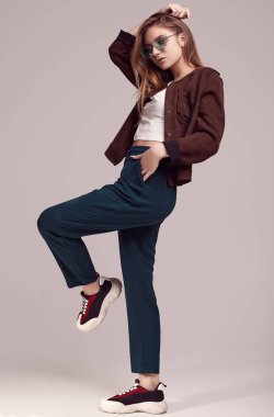 Sevimli Genç kız bardaklarda gri arka plan üzerinde poz moda ceket ve renk portresi. Stüdyo çekimi.