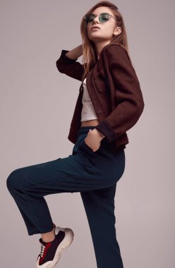 Sevimli Genç kız bardaklarda gri arka plan üzerinde poz moda ceket ve renk portresi. Stüdyo çekimi.