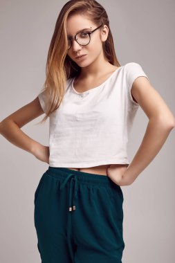 Beyaz gömlek ve gri arka plan üzerinde poz Gözlük Sevimli Genç kız portresi. Stüdyo çekimi.