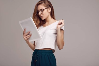 Beyaz gömlek ve dijital tablet gri arka plan üzerinde tutarak Gözlük Sevimli Genç kız portresi. Stüdyo çekimi.