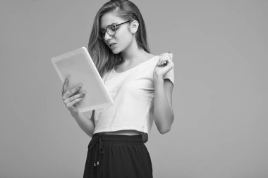 Beyaz gömlek ve dijital tablet gri arka plan üzerinde tutarak Gözlük Sevimli Genç kız portresi. Stüdyo çekimi.