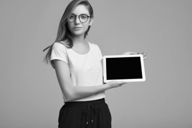 Beyaz gömlek ve dijital tablet gri arka plan üzerinde tutarak Gözlük Sevimli Genç kız portresi. Stüdyo çekimi.
