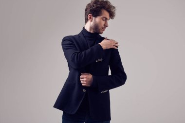 Moda portre Studio gri arka plan üzerinde takım elbise ve gözlük takıyor kıvırcık saçlı yakışıklı zarif biri