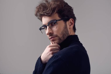 Moda portre Studio gri arka plan üzerinde siyah boğazlı kazak ve gözlük takıyor kıvırcık saçlı yakışıklı zarif biri