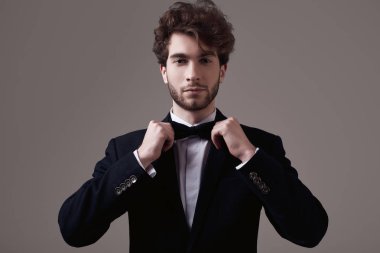 Kıvırcık saçlı Studio gri arka plan üzerinde poz smokin giymiş yakışıklı zarif adam portresi moda