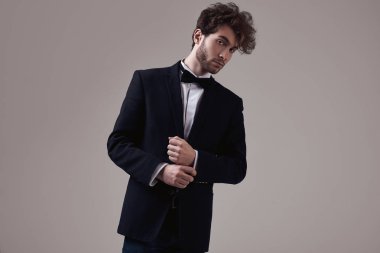 Kıvırcık saçlı Studio gri arka plan üzerinde poz smokin giymiş yakışıklı zarif adam portresi moda