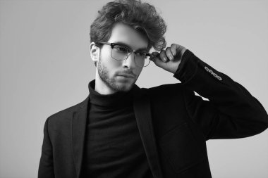 Moda portre Studio gri arka plan üzerinde takım elbise ve gözlük takıyor kıvırcık saçlı yakışıklı zarif biri
