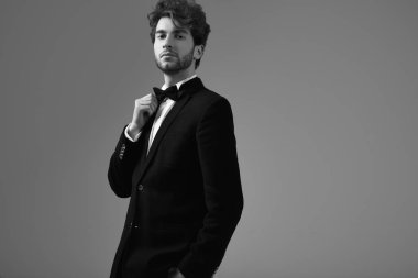 Kıvırcık saçlı Studio gri arka plan üzerinde poz smokin giymiş yakışıklı zarif adam portresi moda