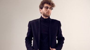 Moda portre Studio gri arka plan üzerinde takım elbise ve gözlük takıyor kıvırcık saçlı yakışıklı zarif biri