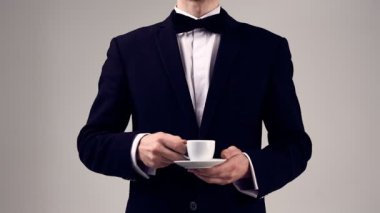 Kıvırcık saçlı bir fincan espresso Studio gri arka plan üzerinde tutarak smokin giymiş yakışıklı şık erkek moda portre