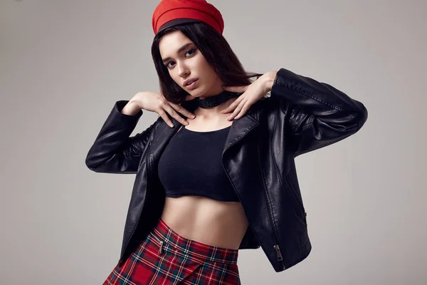 Fashion brunette woman wearing a leather jacket and red hat — Stock Photo, Image
