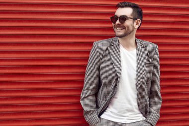 Kırmızı kapının yanında takım elbiseli, yakışıklı, vahşi bir adam.