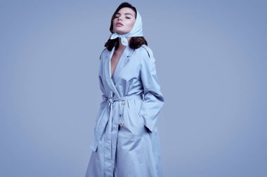 Paltolu ve şallı zarif esmer kadın stüdyoda poz veriyor.