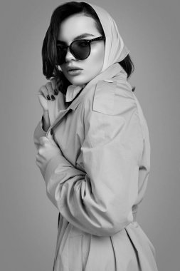 Paltolu ve şallı zarif esmer kadın stüdyoda poz veriyor.