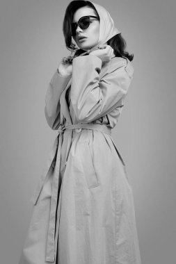 Paltolu ve şallı zarif esmer kadın stüdyoda poz veriyor.