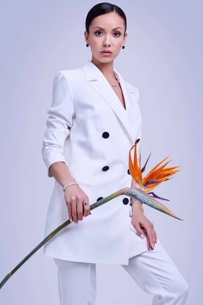 Gorgeous latin women in fashion white suit with exotic flower — Stock Photo, Image