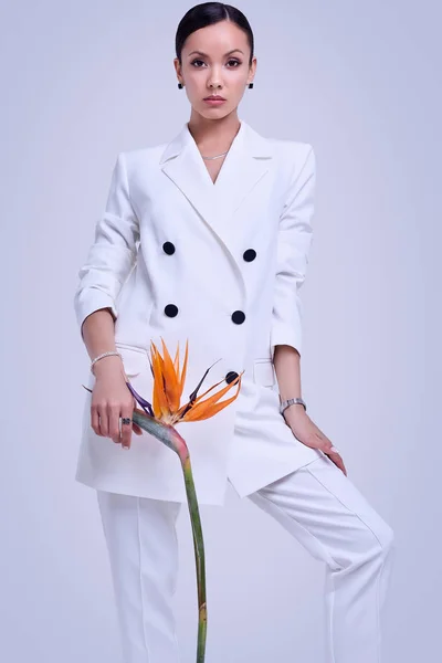 Gorgeous latin women in fashion white suit with exotic flower — Stock Photo, Image