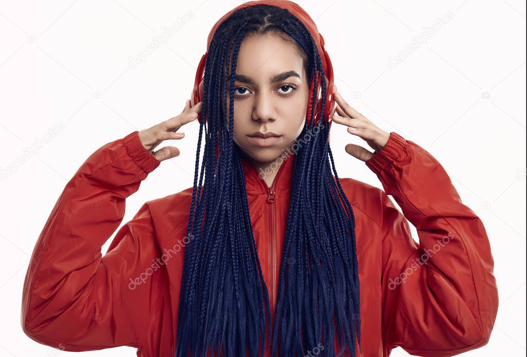 African teenage girl with dreadlocks in red windbreaker listenin