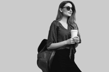 Sırt çantalı, seyahat etmeye hazır güzel bir kadının portresi. Gülümseyen öğrenci kız tatile çıkıyor. Gri arkaplanda izole.