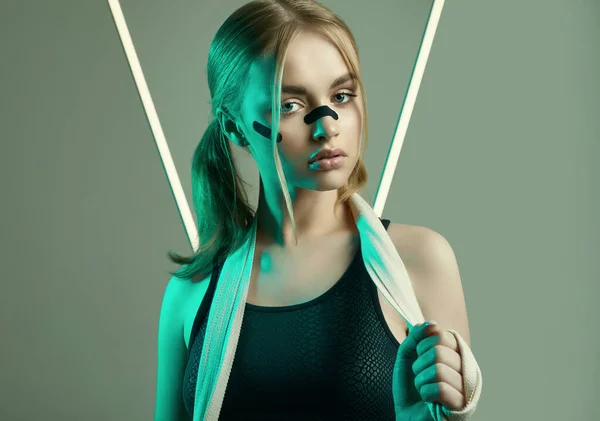 Vivid portrait of strong beautiful girl with blonde hair, sports figure, confident look and fists in protective boxing bandages posing on colorful neon light background