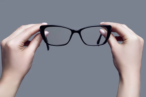 Kép Kezekről Amint Szemüveget Tartanak Egy Szürke Stúdió Háttere Előtt — Stock Fotó