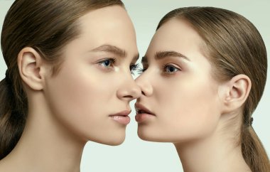 Açık tenli ve kusursuz makyajlı iki esmer kızın stüdyo portresi.