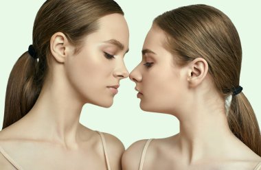 Açık tenli ve kusursuz makyajlı iki esmer kızın stüdyo portresi.