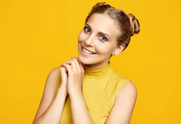 Positive portrait of gorgeous blonde hipster woman model with curly hair posing on colorful yellow background in studio