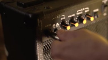 Gitar kablosunu bir amplifikatöre bağlıyorum. Yakın plan..
