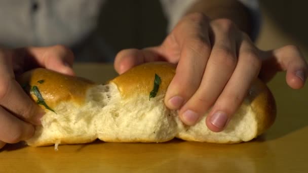 白人男性のパン屋は白いパンをハーブとニンニクで2つの部分に分けています 破壊的なパンのクローズアップ — ストック動画