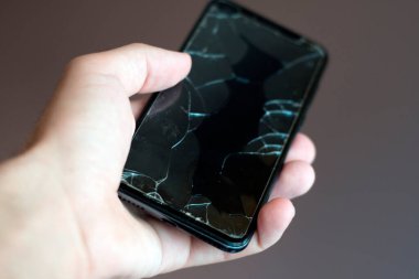 Bir adamın elinde kırık bir ekranla telefon. Bozuk bir akıllı telefonun yakın çekimi.