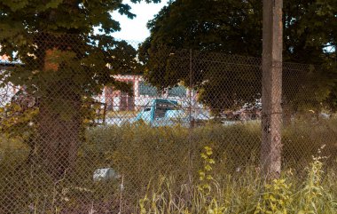 Terk edilmiş Çernobil şehrinde terk edilmiş mavi bir uçak gemisi. Seçici odaklanma. Çalılıklardaki araba..