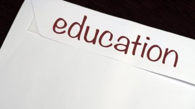 Ahşap masanın üzerinde üzerinde yazılı olan beyaz bir zarf var. Yüz dolarlık banknotlar masaya düşüyor. Mali durumunuzu idare etmek ve para biriktirmek. Kapat.