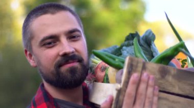 Çiftçi, sebze dolu tahta bir kutuyla organik tarlada yürüyor. Bahçedeki gülümseyen beyaz sakallı adamın portresi. Ağır çekimde yakın çekim