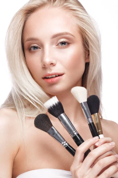 Beautiful young girl with a light natural make-up, brushes for cosmetics and nude manicure. Beauty face. — Stock Photo, Image